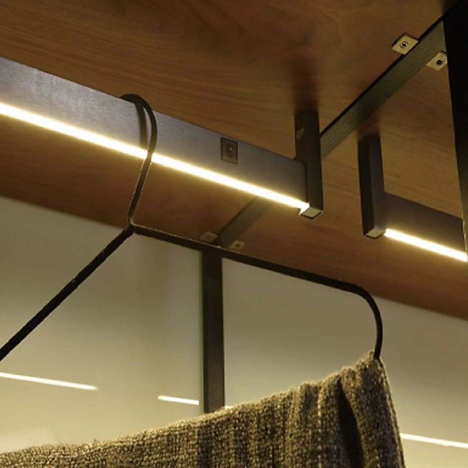 Lysstang wardrobe LED profile under a shelf lighting a hanging garment in a wardrobe